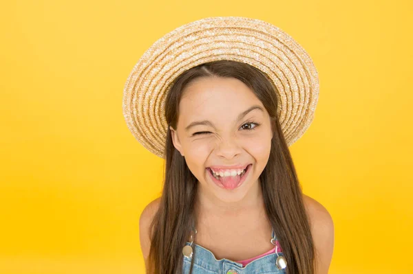 夏の帽子の黄色の背景で幸せな陽気な子供。笑えるわ。帽子の素晴らしい女の子。陽気な顔だ。感情的な子供だ。夏休みだ。ファッショナブルな服装。休暇を楽しんで。夏のファッション — ストック写真