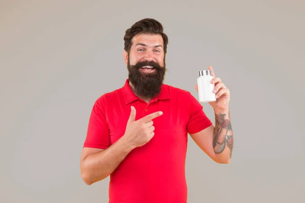 Side effects. Medicines concept. Food additives vitamins for male health. Vitamin complex. Handsome bearded man take medication. Health care. Hipster hold plastic container. Investment in health