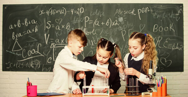 Test tubes with colorful liquid substances. Study of liquid states. Group school pupils with test tubes study chemical liquids. Science concept. Girls and boy providing experiment with liquids