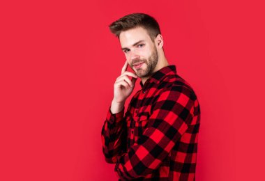 Vahşi Batı onun kalbi. Sakallı ve kıllı yakışıklı sıradan bir adam. Neşeli ve şık. Kırmızı arka planda yakışıklı bir adam. Seksi Avrupalı iş adamının kapalı mekan portresi. kendinden emin ve sakin