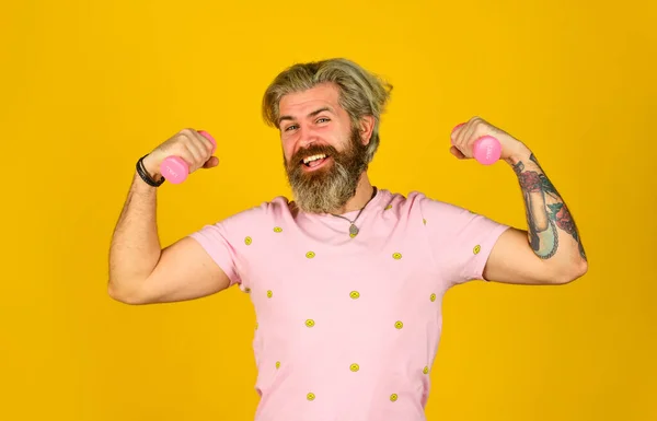 Entraînement avec haltère. mâle à la salle de fitness. pratiquer l'haltérophilie. puissance et force. hipster montrer biceps muscle. barbu gars tenir équipement de sport lourd. sportif en bonne santé. homme heureux utiliser haltère. — Photo