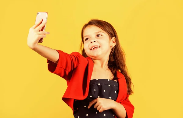 Szelfi idő. Kis lány, hogy szelfi okostelefon sárga háttér. Kis gyerek szelfi kamera a mobiltelefonban. Élvezi szelfi ülés divat stílusban. Kommunikáció online. Közösségi hálózat — Stock Fotó