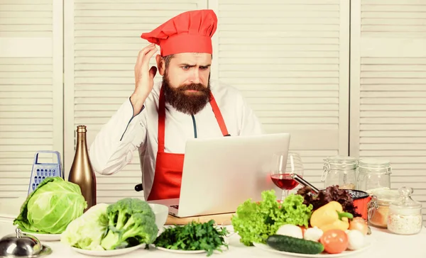 Culinary education online. Elearning concept. Man chef searching internet recipe cooking food. Chef laptop read culinary recipes. Culinary school. Hipster in hat and apron learning how to cook online