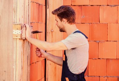 Bina ve inşaat. Çekiç aletli bir mühendis. Genel bakım ve onarım işçileri bakım ve onarım işleri için işe alınır. Çekiç kullan. Çekiç tuğlalı arka planı olan bir işçi