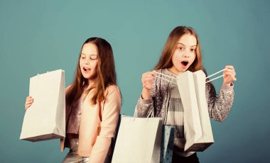 Çocuk modası. Mavi arka plan. Satış ve indirimler. Kardeşlik ve aile. Satın almada tasarruf. Alışveriş çantalı küçük kızlar. Mutlu çocuklar. Küçük kız kardeşler. Çocuk tarzı. Çocuk mağazası. sürüsü olan çocuk