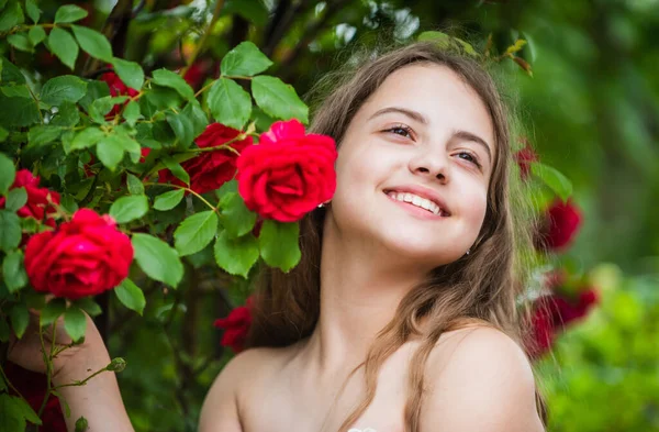 Impossible to hide her happiness. child enjoy blossom in park. small angel for bride. cute lady. happy childhood. beauty and fashion. pretty kid smell rose flower. spring and summer nature — Stock Photo, Image