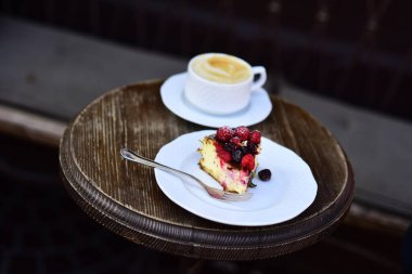 Böğürtlenli cheesecake ve ahşap masada kahve.