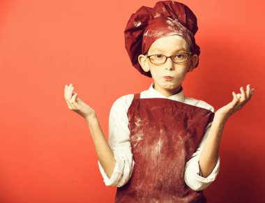 Kırmızı stüdyo arka planında lekeli aşçı çocuk.