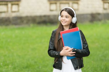 Kulağa hoş gelen bir ders. Küçük öğrenci kulaklık takıyor. Küçük çocuk ders için kitapları tutuyor. Özel ders. Dinleme becerileri. Müzik dersi. Okul ve eğitim