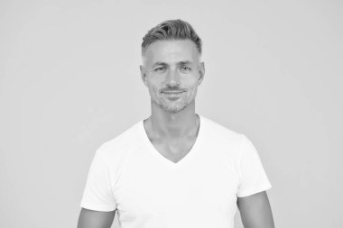 Yakışıklı adam. Adam sarı arka plan. Sakallı ve saç tıraşlı traşsız bir adam. Erkekler tımar ediliyor. Berber dükkanı. Sıradan tarzda yakışıklı bir adam. Moda ve tarz