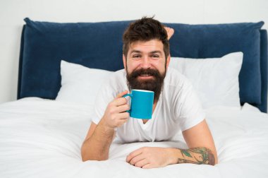 Uyan ve kahveyi kokla. Mutlu hipster sabahları kahve içer. Sakallı adam yatakta kahveyi sever. Sıcak içecek. Kahvaltılık çay. Rahatlatıcı ruh hali. Günaydın kahveyle başlıyor.