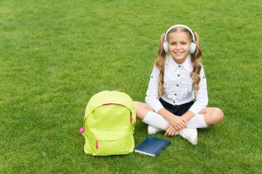 Küçük kız kitabı tutuyor. Çocuklar için edebiyat. Çocukluk gelişiyor. Defterle çalış. Okula dönüyorum. Çocuk parkta ders çalışıyor. Kitapla birlikte yeşil çimlerin üzerinde rahatla. çevrimiçi müzik dinlemek