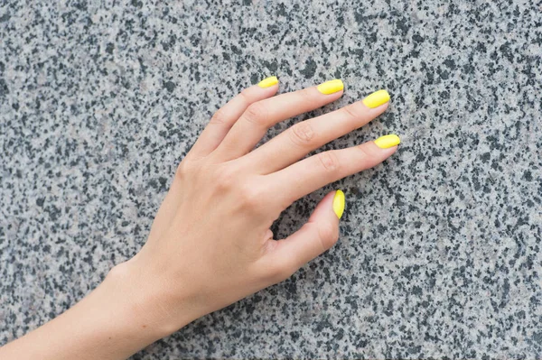 Professional nail care. Female hand with yellow nail color. Applying nail lacquer. Nail salon manicure. Acrylic overlays and extensions. Cosmetic beauty treatment for fingernails