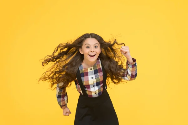 Air in her hair. natural beauty. Girl kid long hair flying in air. Child with natural beautiful healthy hair yellow background. Tips for healthy hair. Hairdresser salon. Beauty procedure. Extra light