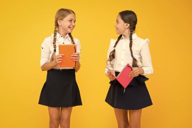 İyi kitaplar iyi anları yakalar. Sarı arka plan üzerinde renkli kapakları ile kitap tutan sevimli küçük çocuklar. Ansiklopedisi ya da çocuk kitapları olan küçük kızlar. Okullar için eğitim kitapları