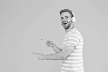 Kahramanca müzik dinlemek, daha pozitif hissetmek, aktif ve ilham verici. Adam kopyalama alanını işaret ediyor. Mükemmel bir fikir. Happy Man müzik kulaklığı dinler. Kablosuz kulaklıklar. Enstrümantal müzik