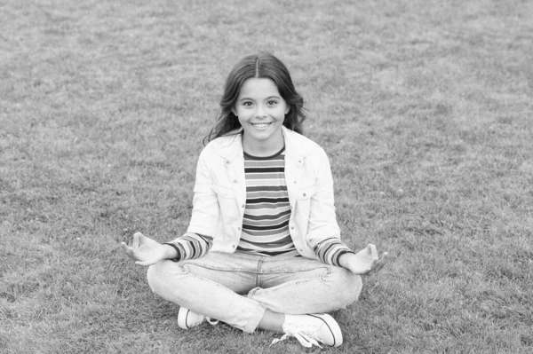 Peace of mind. School break for rest. Adorable pupil. Girl kid sit on lawn. Girl school uniform enjoy relax. Importance of relaxation. Little schoolgirl. Relax at school yard. Kid relaxing outdoors