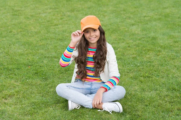 Tempo libero. moda per bambini. giornata di sole primaverile. allegra studentessa rilassarsi sull'erba verde. bambino allievo sorridente indossare stile casual. Torniamo a scuola. felice giorno dei bambini. piccola ragazza all'aperto — Foto Stock