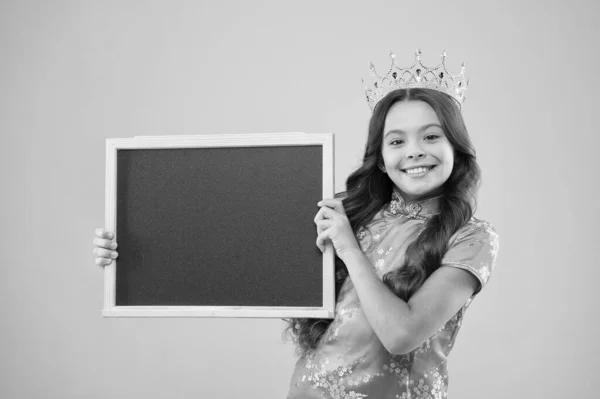 happy childhood. cheerful princess hold school blackboard. School of success. school prom party advertising. Prom queen hold school board, copy space. coronation beauty party. Pride and glory