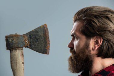 Mükemmel erkek. Keresteci, kırmızı kareli gömlekli, vahşi sakallı adam. Tıraş konsepti. Cadılar Bayramı. Adam elinde bir balta tutuyor. Baltası olan sakallı bir oduncu. Ekose gömlekli bir oduncu.