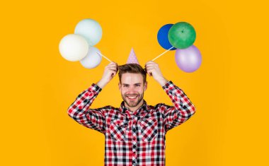 Katıksız parti meraklısı. Doğum günü şapkalı komik adam. Adam balon tutuyor. Mutlu bayramlar. Eğlence ve hediye zamanı. Mutlu yıllar veya yıldönümleri. Neşeli ve neşeli hisset
