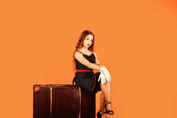 Beautiful female. small child relax on vintage baggage. travel bag accessory. wanderlust and adventure. traveler kid sit on vintage suitcase. travel concept. pinup girl sit on luggage — Stock Photo, Image