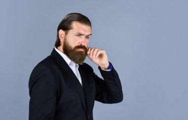 Ciddi sakallı iş adamı. Modern görünümlü şık, olgun bir adam. Erkek ceketi dolabı. Takım elbiseli şık bir adam. Resmi manken. Gri arka planda duran yakışıklı adam. Boşluğu kopyala