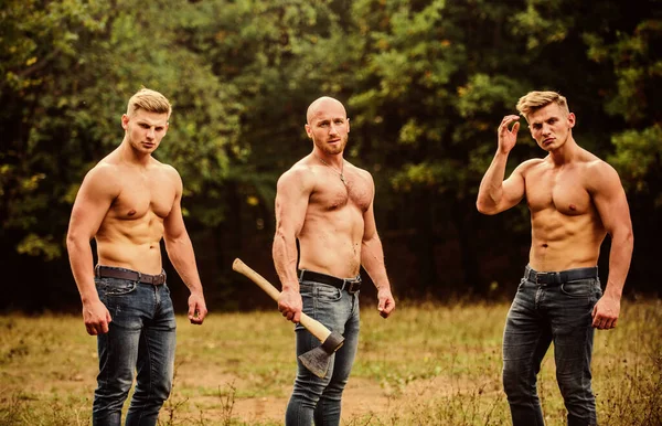 Taking break. brutal guys pose with naked torso. handsome guys with sexy body. Sports and leisure. mesomorph. three muscular men with axe. athletic man use ax. bodybuilders in jeans. Three sexy guys — Stock Photo, Image