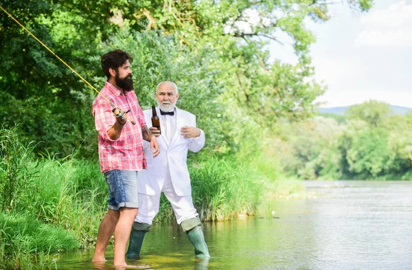 Set up rod with hook line and sinker. Fishing and drinking beer. Men relaxing nature background. Fun and relax. Weekend time. Bearded man and elegant businessman fishing together. Fishing skills Stock Picture