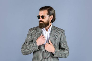 Erkek güzellik ve moda. Mükemmel sakallı ve bıyıklı acımasız bir iş adamı. Ceketli gerçek patron. Olgun adam gözlük takıyor. Güven ve karizma. Yakışıklı adam ofis kıyafeti giyer. Kendine güveni tam