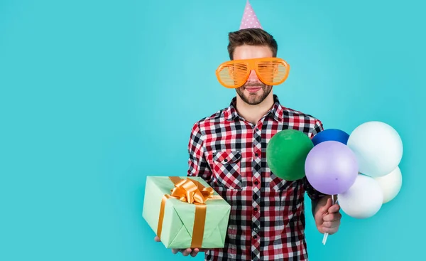 Handlar i köpcentret. Rolig man i födelsedagshatt. Killen håller festliga ballonger. Glad högtid firande. Dags för skoj och presenter. Grattis på födelsedagen eller årsdagen. Känn glädje och glädje. ren sällskapsgås — Stockfoto