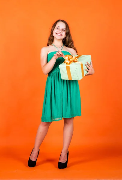 lets celebrate holiday. child in summer day on orange background. its shopping time. small girl hold present box. little kid with gift box. happy birthday party. childhood happiness. Clothing store