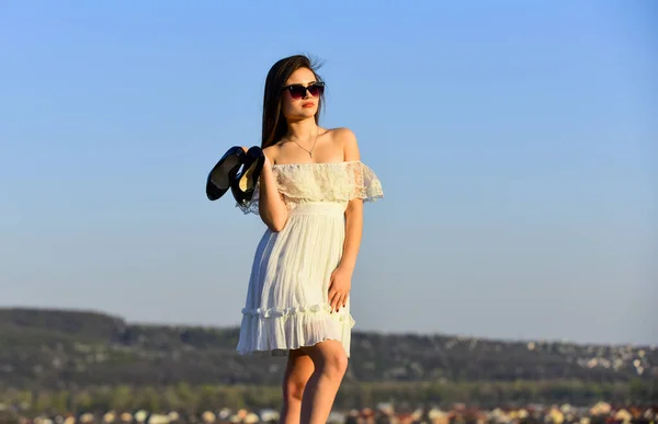 Vacanze estive. Ragazza in occhiali da sole copiare spazio. Verso l'estate. Concetto post-party. L'alba delle donne porta i tacchi alti in mano. Donna sul sole mattina cielo blu. Modello tenero abito estivo. Libertà — Foto Stock