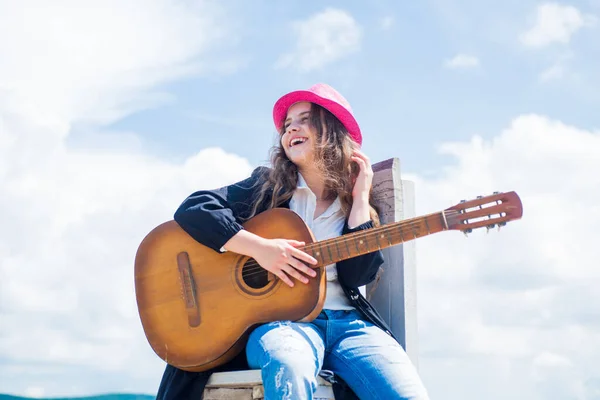 Un gamin talentueux. style country. instrument de musique à cordes. jouer de la guitare acoustique. petite fille joue de la guitare elle aime la musique. cours de musique. petit guitariste sur fond de ciel — Photo