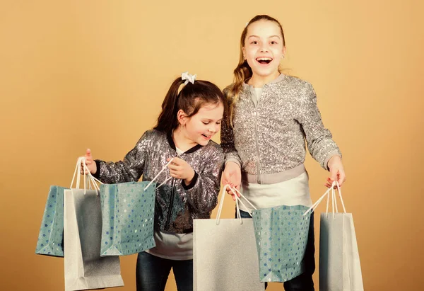 Día de compras. Los niños sostienen paquetes. Moda infantil. Espera más. Paga menos. Chicas hermanas amigas con bolsas de compras de fondo beige. Compras y compras. Viernes Negro. Venta y descuento —  Fotos de Stock