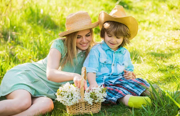 Spring season. Happy holidays. Cowboy family collecting spring flowers. Mother and cute son having fun. Spring holiday. Weekend leisure. Explore nature. Wildflowers in field. Motherhood happiness