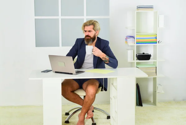 L'homme travaille à la maison pendant la pandémie de coronavirus. homme détendu assis sur une chaise confortable en utilisant un ordinateur portable. en ligne dans les médias sociaux. travailler pieds nus au bureau à domicile. concept de distance sociale — Photo