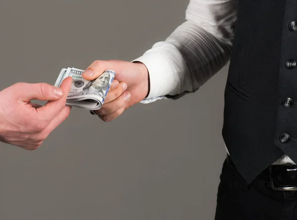 Male clients hand pay, holds money in hand, grey background.