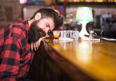 Yorgun suratlı bir adam barda tek başına oturuyor.