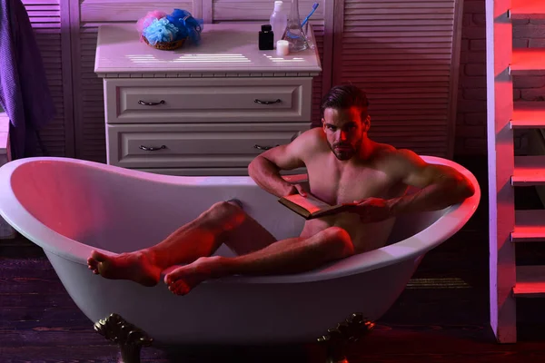 Macho liest Buch nackt in Badewanne mit erotischer Atmosphäre — Stockfoto