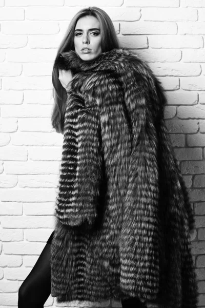 Fashionable sexy woman in fur on brick wall studio background — Stock Photo, Image