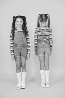 Şık ve kendinden emin. Küçük kızları sarı arka planda karşılaştır. Kuaför salonu. Çocuk yaz modası. Güzellik ve tarz. çocukluk hayatı. Mutlu okul arkadaşlığı. En iyi arkadaşlar. Küçük kız kardeşler eğlenin.