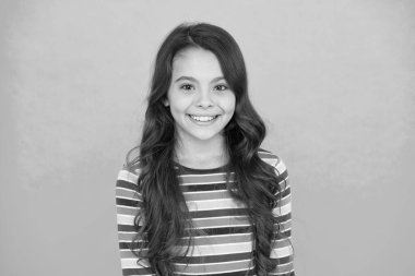 Ateş gibi saçlar. Olumlu duygularını ifade et. Mutlu küçük kız turkuaz arka plan. Neşeli liseli kızın uzun kıvırcık saçları var. Renkli elbiseli bir çocuk. Çocuk bahar modası. Küçük güzel iyimser.