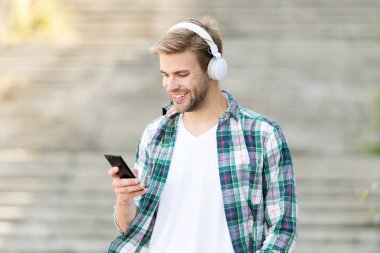 Dış dünyayla bağlantıyı kes. Mutlu adam cep telefonuyla video görüşmesi yapıyor. Yakışıklı adam telefonda müzik dinlerdi. Akıllı telefon. Müzik çalar. MP3. Telefondaki müzik uygulaması. Yeni teknoloji. Modern hayat
