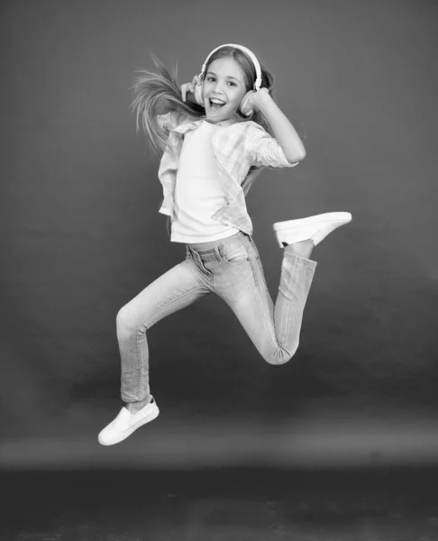 Little girl in earphones. reach her dream. jump up in air. achievement. ecstatic little girl wear earphones. show dance move. childhood happiness. happy kid listen music. energetic song for activity