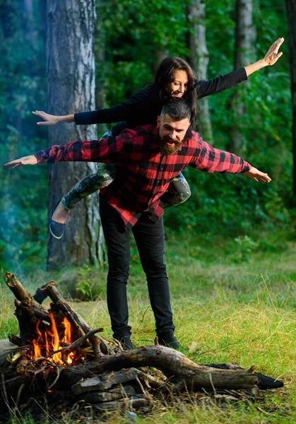 Man carrying happy cheerful girlfriend on back like plane