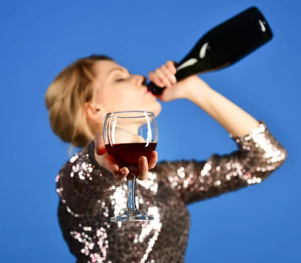 Corporate party. Lady drinks wine from bottle on blue background