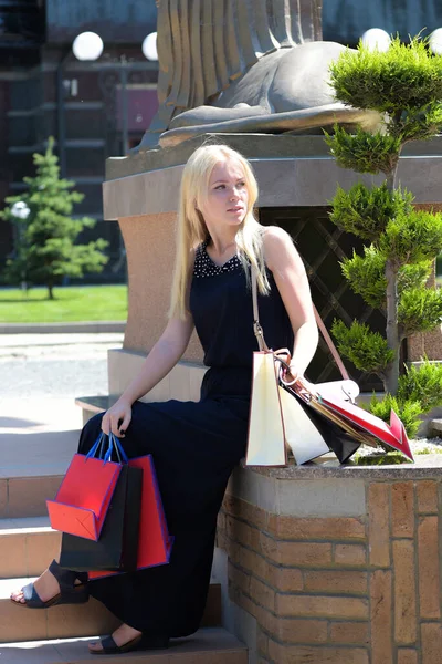 Señora con el pelo rubio y la cara tranquila sostiene bolsas de compras — Foto de Stock