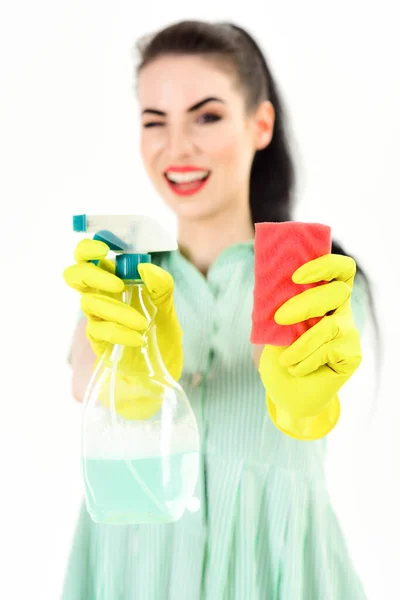 Servicio de limpieza y concepto de trabajo. Mujer guiña y sostiene esponja y spray para el hogar . —  Fotos de Stock