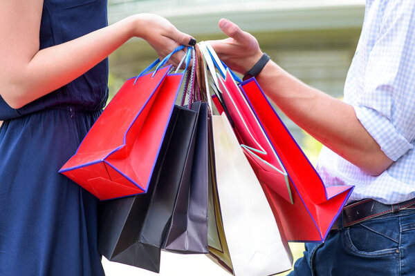 Красочные бумажные пакеты в руках пары. Торговля и продажа
.